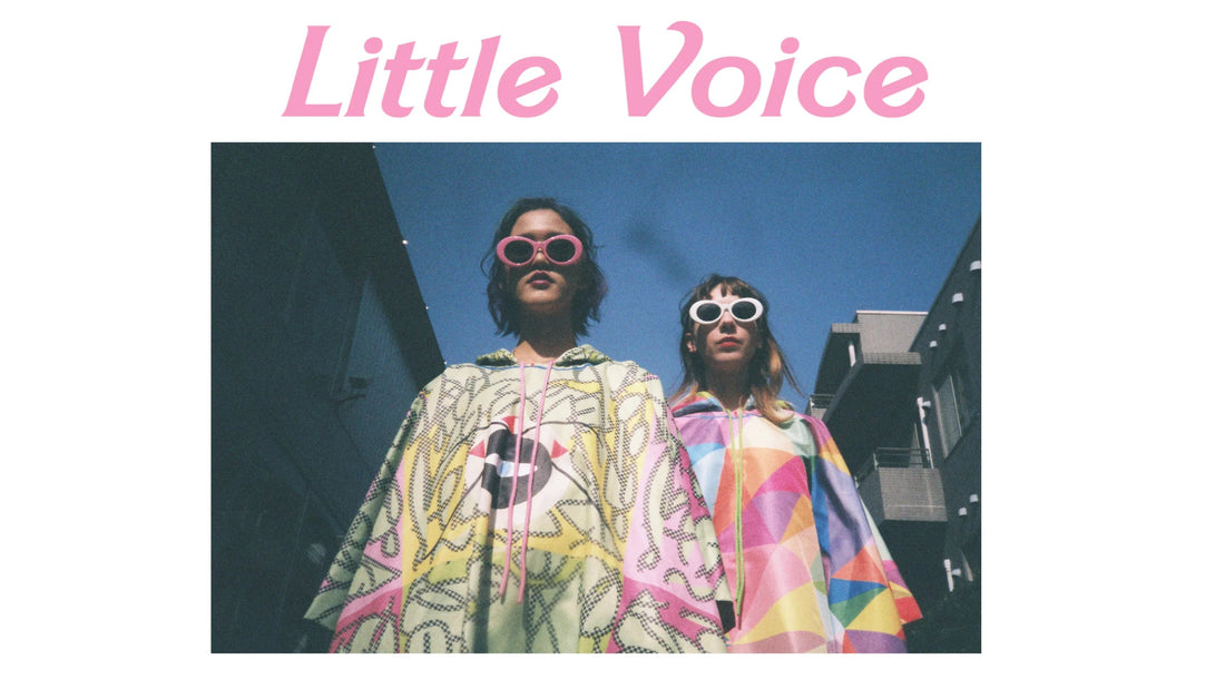 Two women wearing colorful geometric patterned hooded ponchos and sunglasses under a clear blue sky