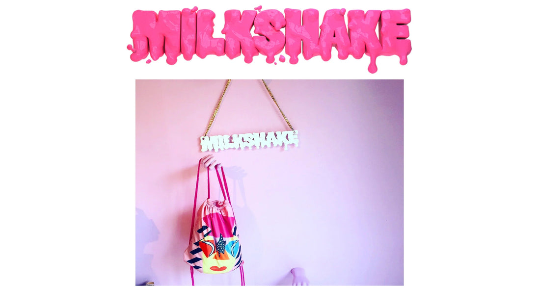 Pink wall with white dripping milkshake sign and a hand holding colorful drawstring bag