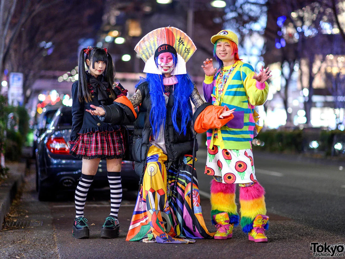 Three young people in colorful, eclectic Harajuku street fashion posing at night on a city street