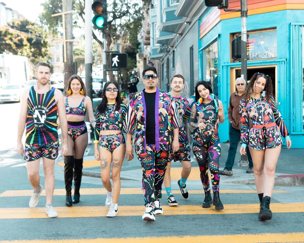 Group of seven diverse adults walking on city street crosswalk wearing colorful, patterned clothing and accessories