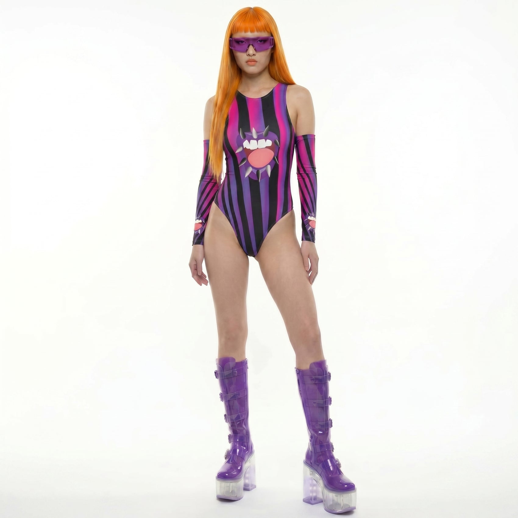 Person wearing a colorful striped bodysuit with a sun design, purple boots, and sunglasses on a white background.