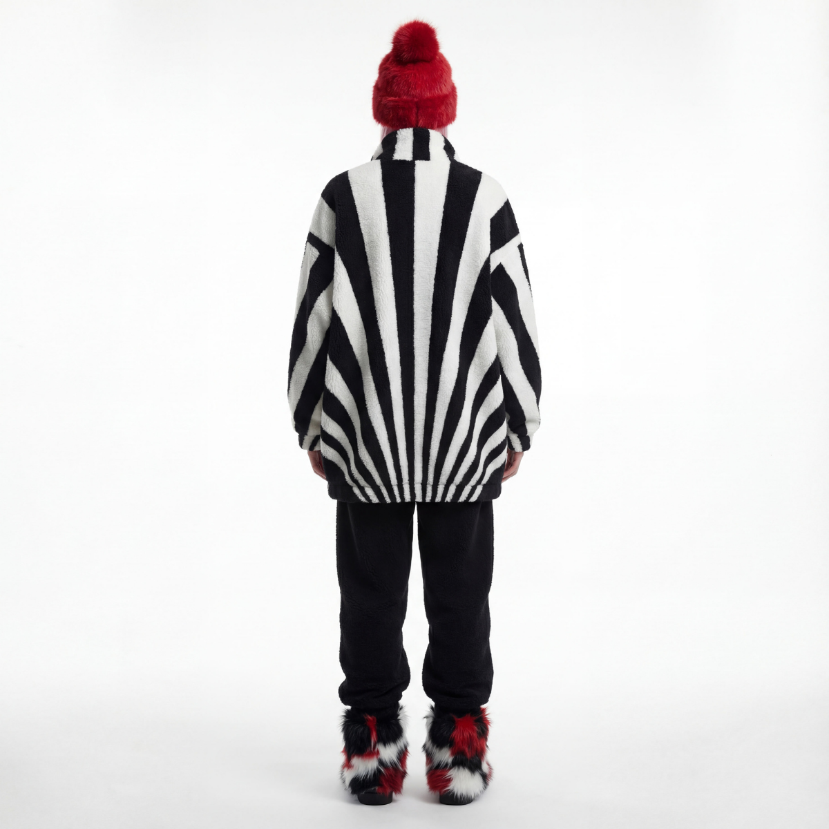 Person wearing a black and white striped sweater with a red beanie on a white background