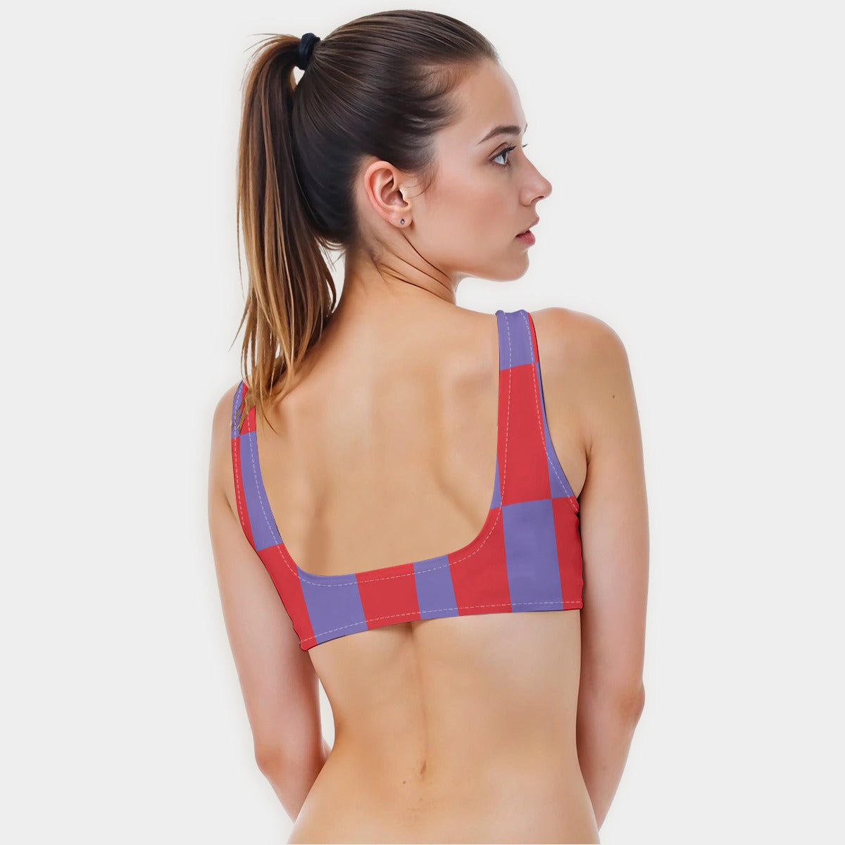 Woman wearing a red and purple checkered sports bra on a white background